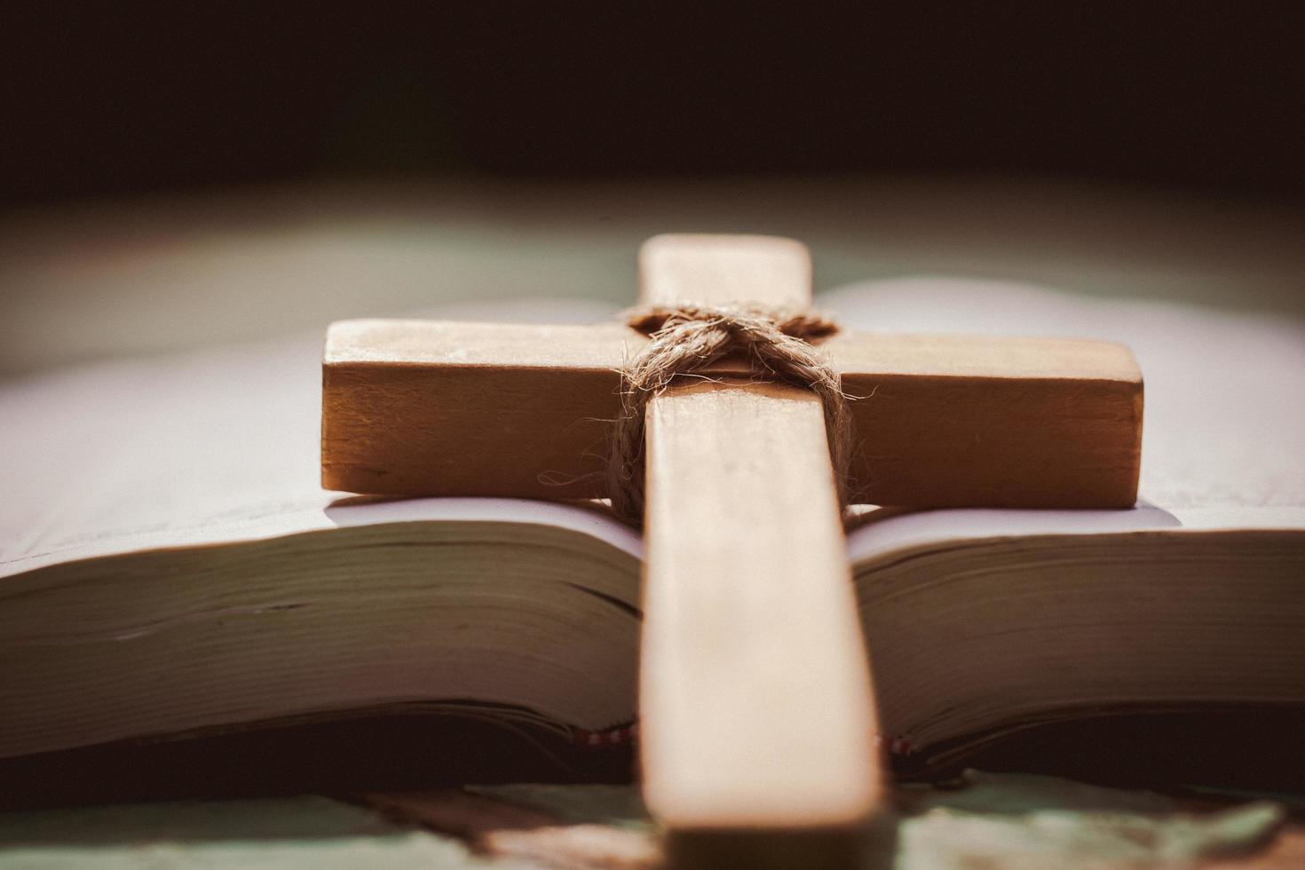 öppen bok på gammalt träbord med kors, religionskoncept, kraft av hopp eller kärlek och hängivenhet religion. foto