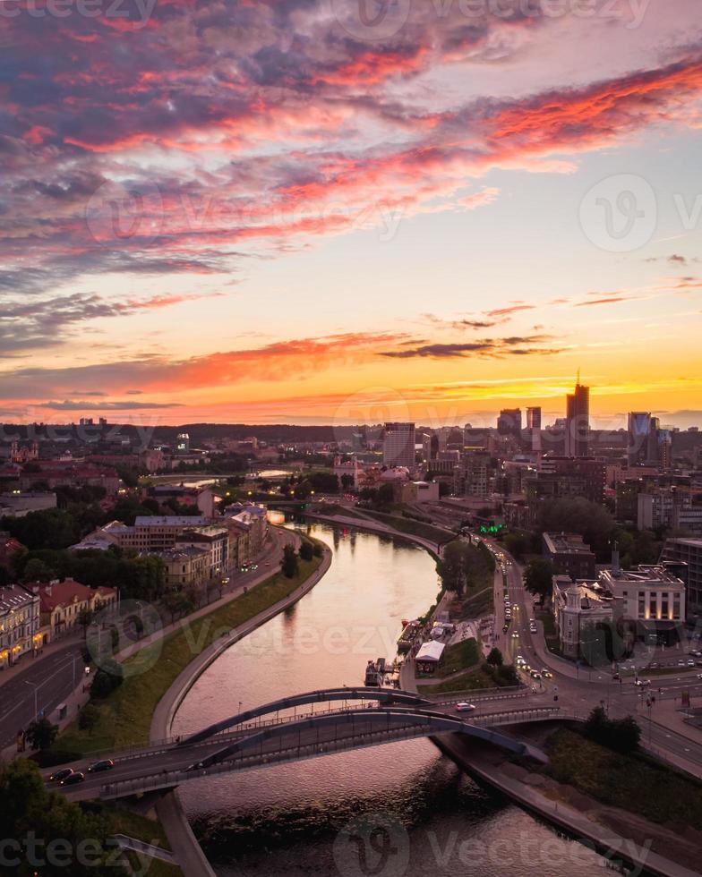 nerisfloden med utsikt över mindaugasbron och affärsdistriktsbyggnader i Litauens huvudstad vilnius vid naturskön solnedgång på sommaren foto