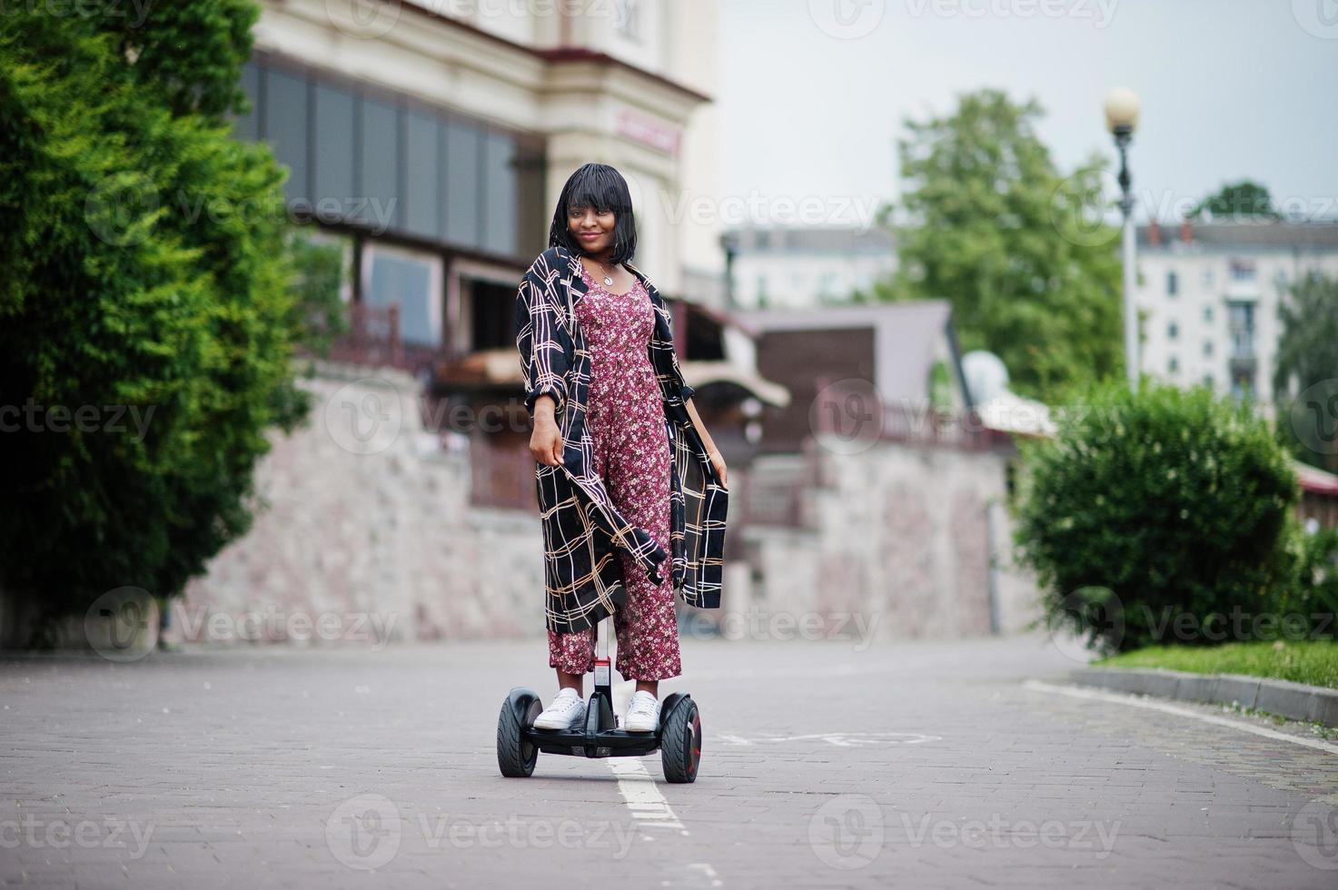 vacker afrikansk amerikansk kvinna som använder segway eller hoverboard. svart flicka på dubbla hjul självbalanserande elektrisk skoter. foto