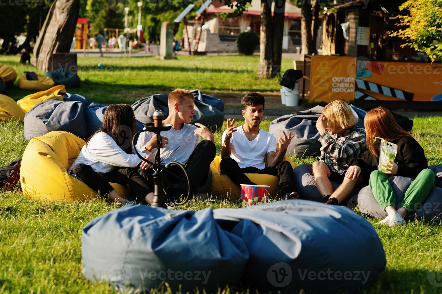 ung multietnisk grupp människor som tittar på film på poff i utomhusbio. foto