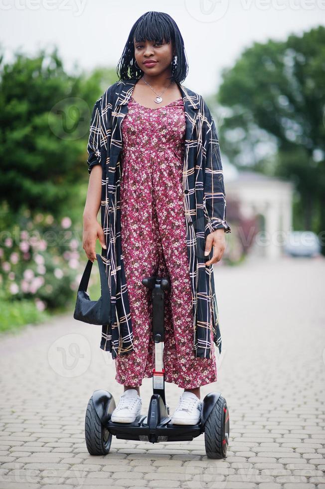 vacker afrikansk amerikansk kvinna som använder segway eller hoverboard. svart flicka på dubbla hjul självbalanserande elektrisk skoter. foto