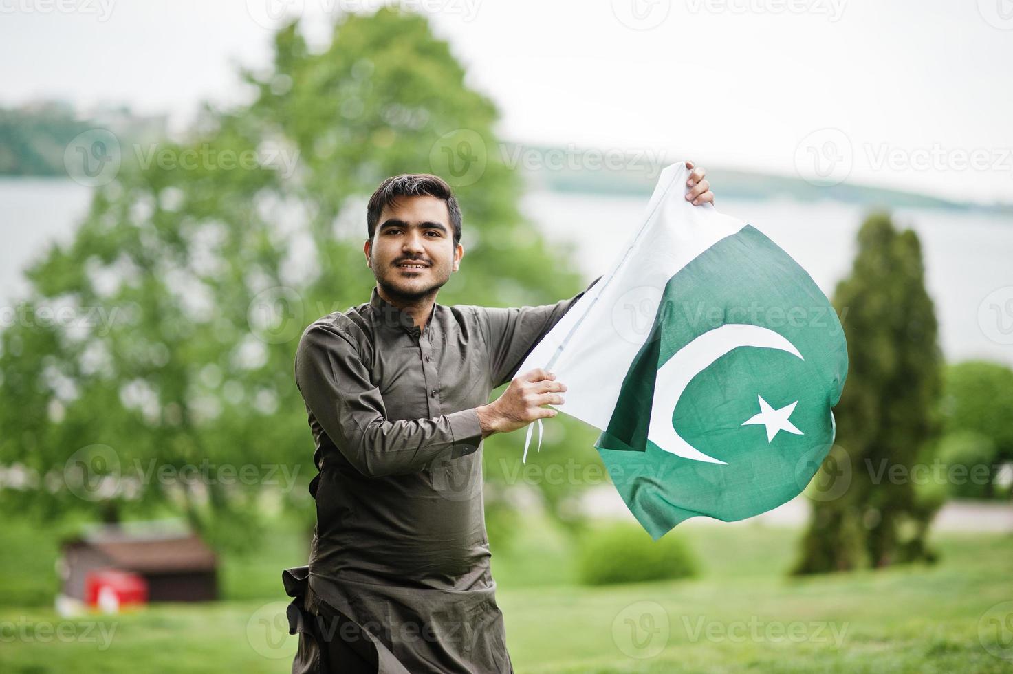 indo pakistansk man bär traditionella kläder achkan eller sherwani med pakistansk flagga. foto