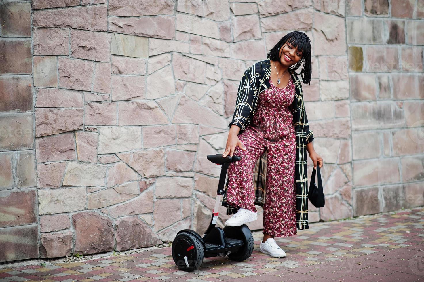 vacker afrikansk amerikansk kvinna står nära segway eller hoverboard. svart flicka med dubbla hjul självbalanserande elektrisk skoter. foto