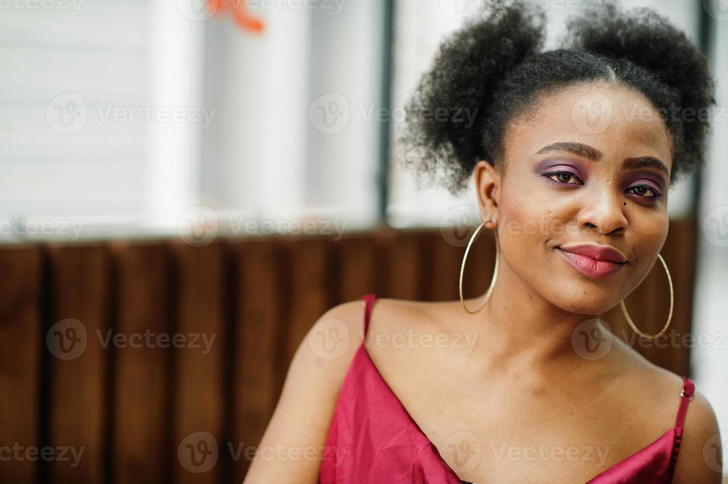 porträtt av en vacker naturlig ung afrikansk kvinna med afro hår. svart modell i röd sidenklänning. foto