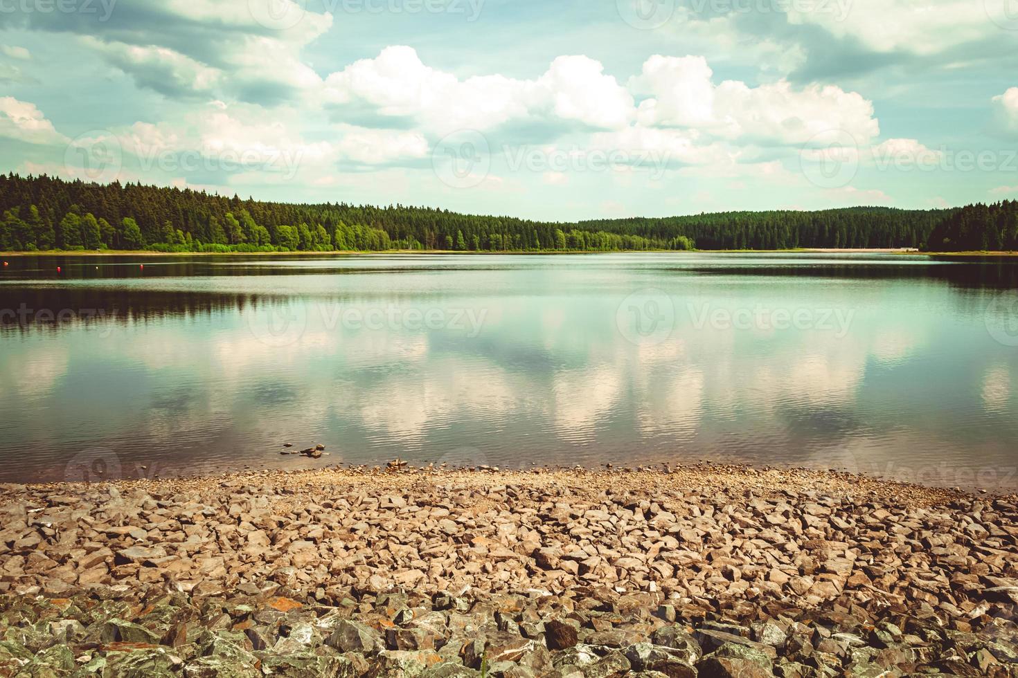 moln reflekteras i en lugn sjö med skogar foto