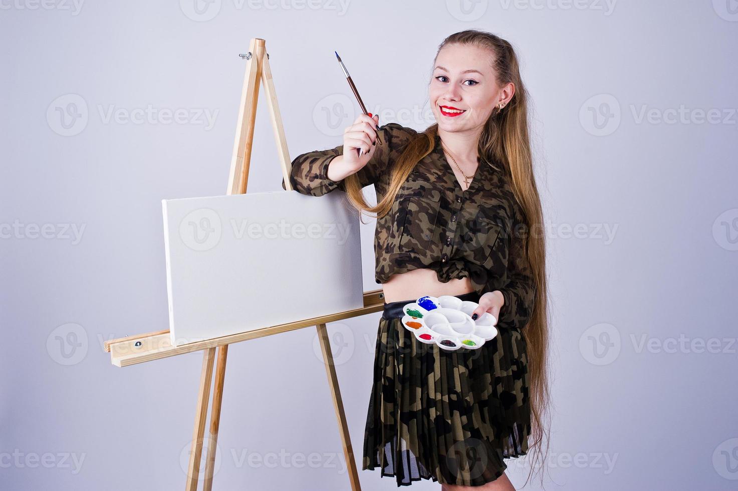 vacker kvinna konstnär målare med penslar och oljeduk poserar i studio isolerad på vitt. foto