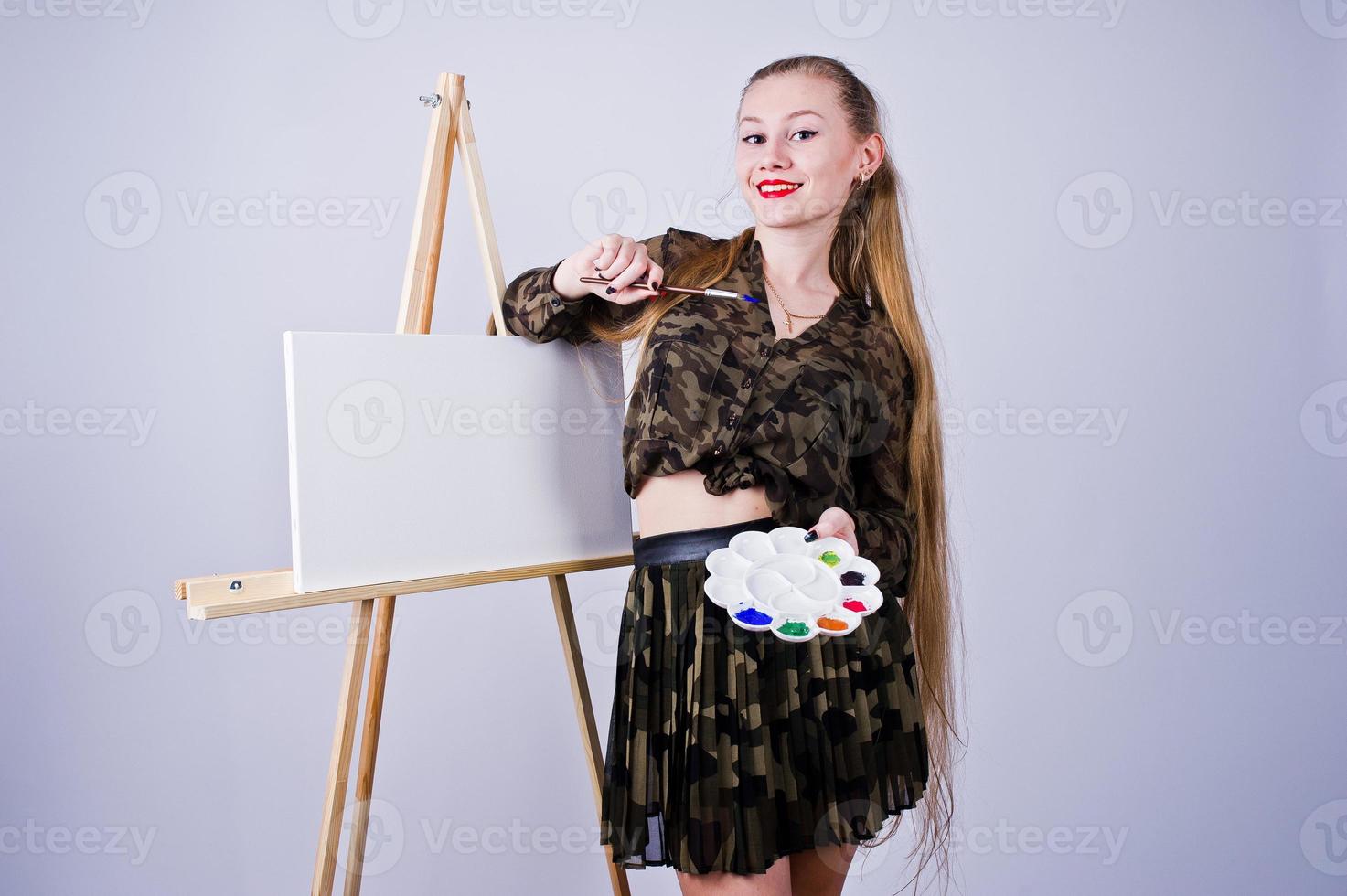 vacker kvinna konstnär målare med penslar och oljeduk poserar i studio isolerad på vitt. foto