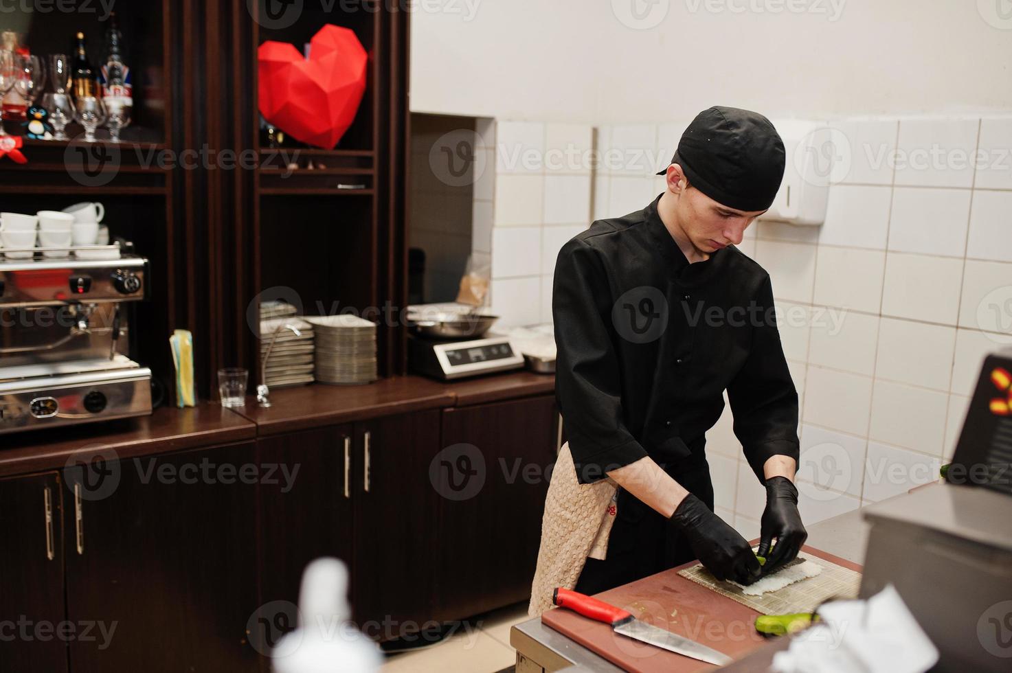 professionella kockkläder i svart gör sushi och rullar i ett restaurangkök med japansk traditionell mat. foto