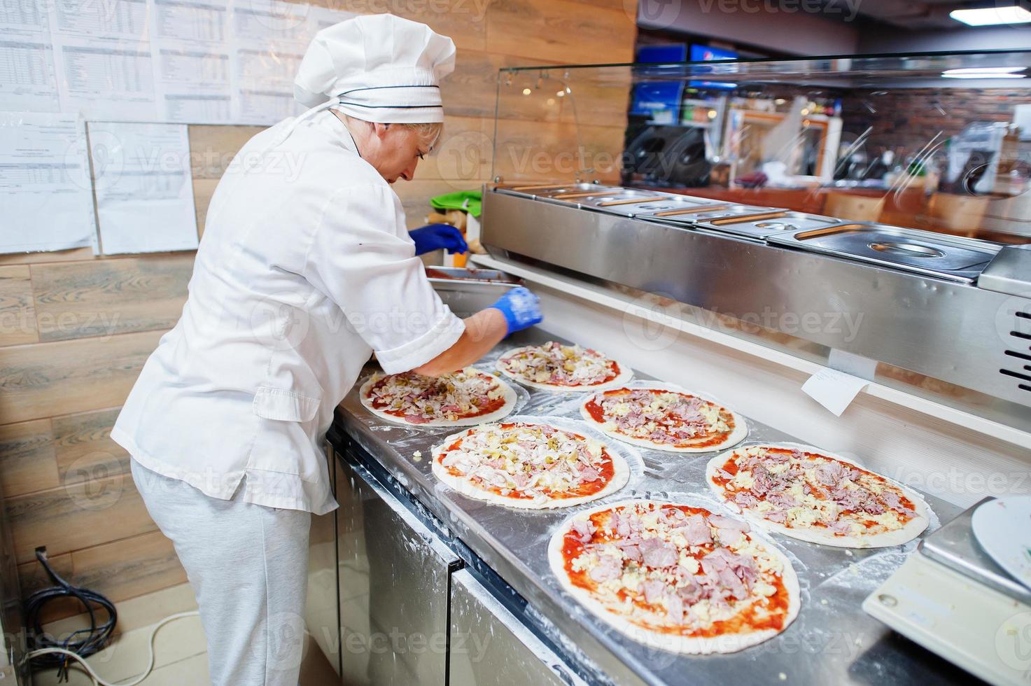 kvinnlig kock förbereder pizza i restaurangkök. foto