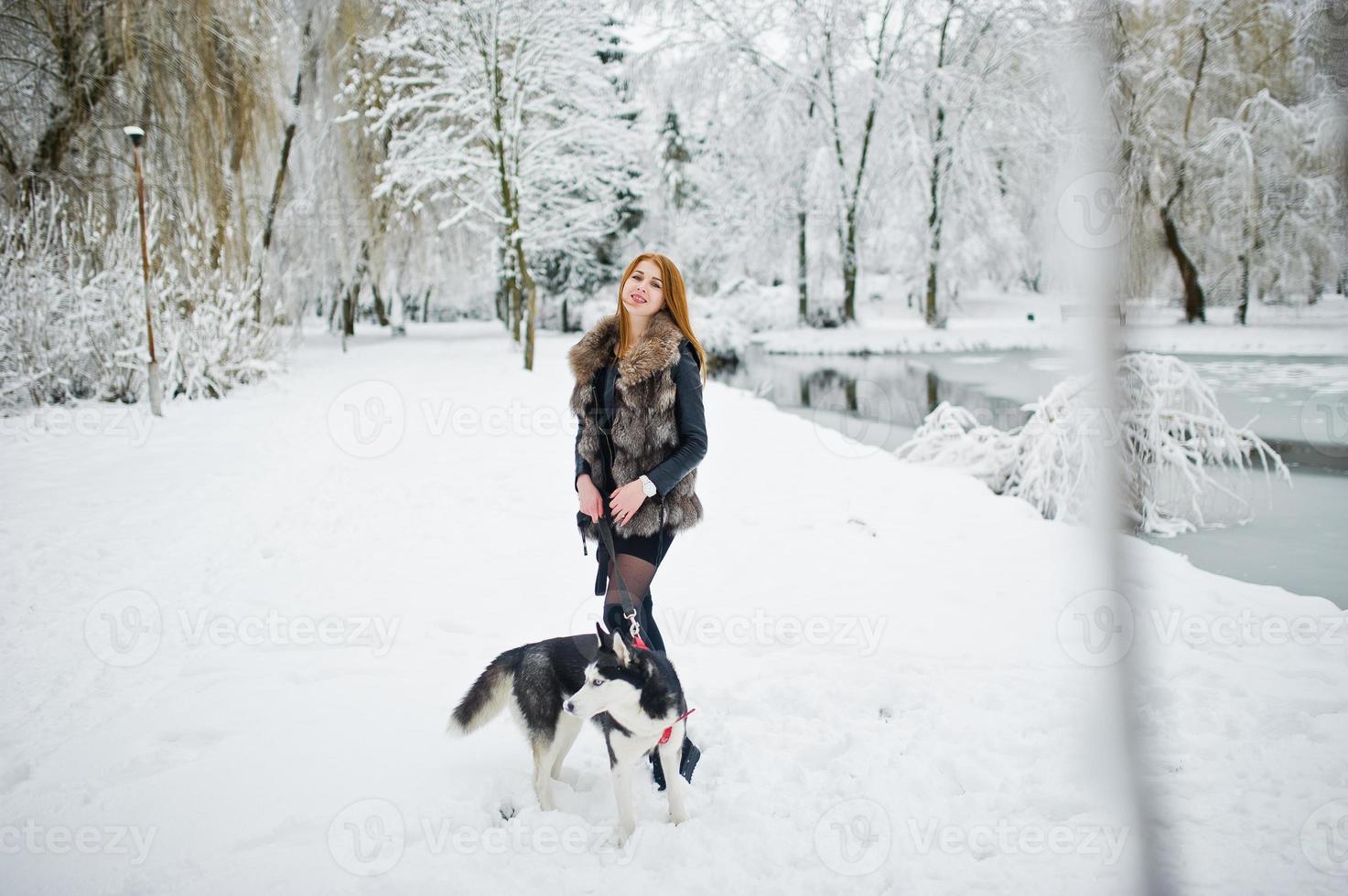 rödhårig tjej går i parken med husky hund på vinterdagen. foto