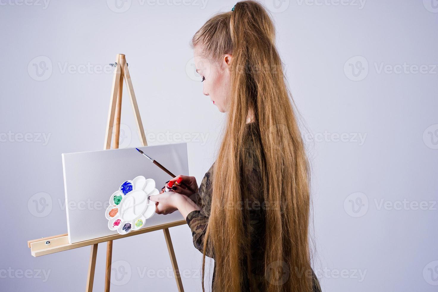 vacker kvinna konstnär målare med penslar och oljeduk poserar i studio isolerad på vitt. foto