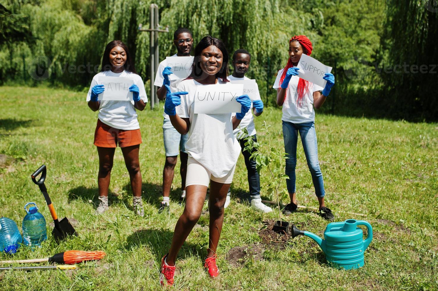 grupp glada afrikanska volontärer håller tom tavla med enhetstecken i parken. Afrika volontärarbete, välgörenhet, människor och ekologi koncept. foto