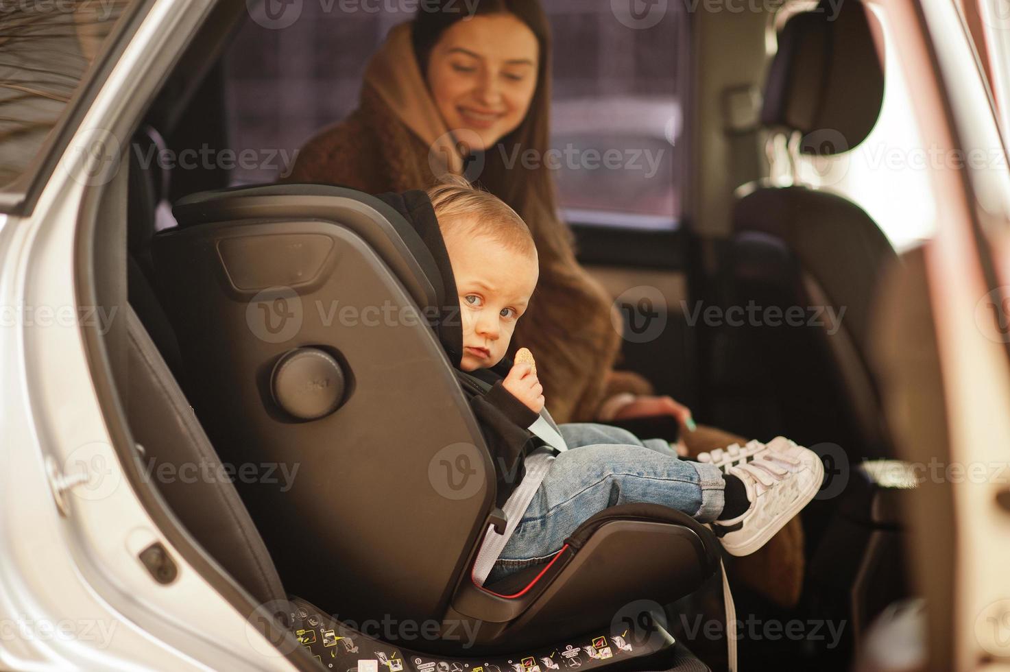 ung mor och barn i bilen. barnstol på stol. säkerhetskörningskoncept. foto