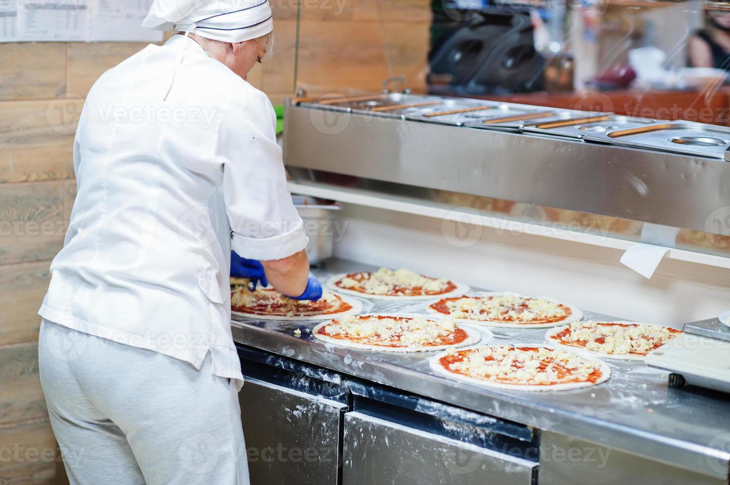kvinnlig kock förbereder pizza i restaurangkök. foto