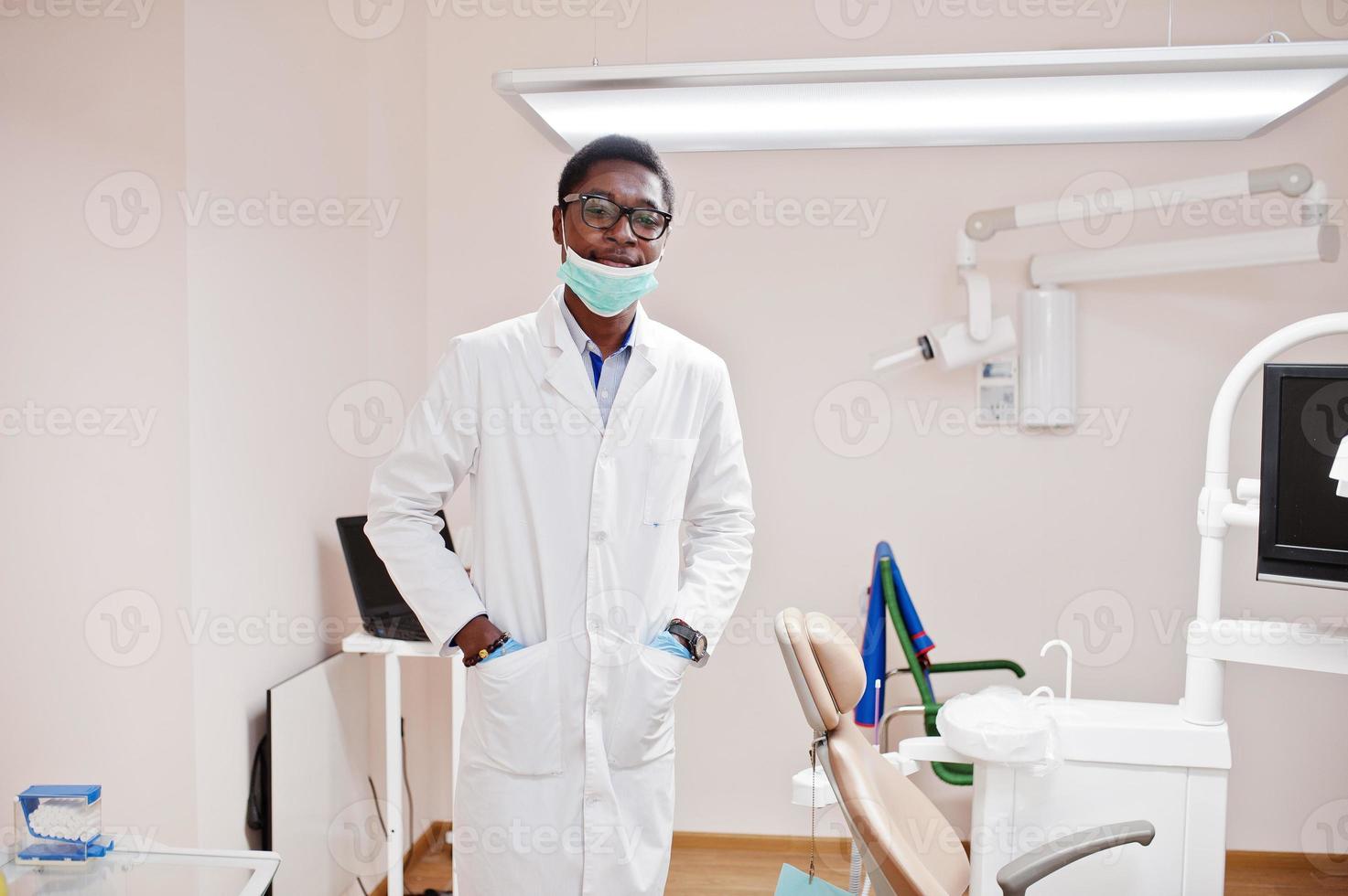 afrikansk amerikansk manlig läkare i glasögon och mask poserade på kliniken. foto