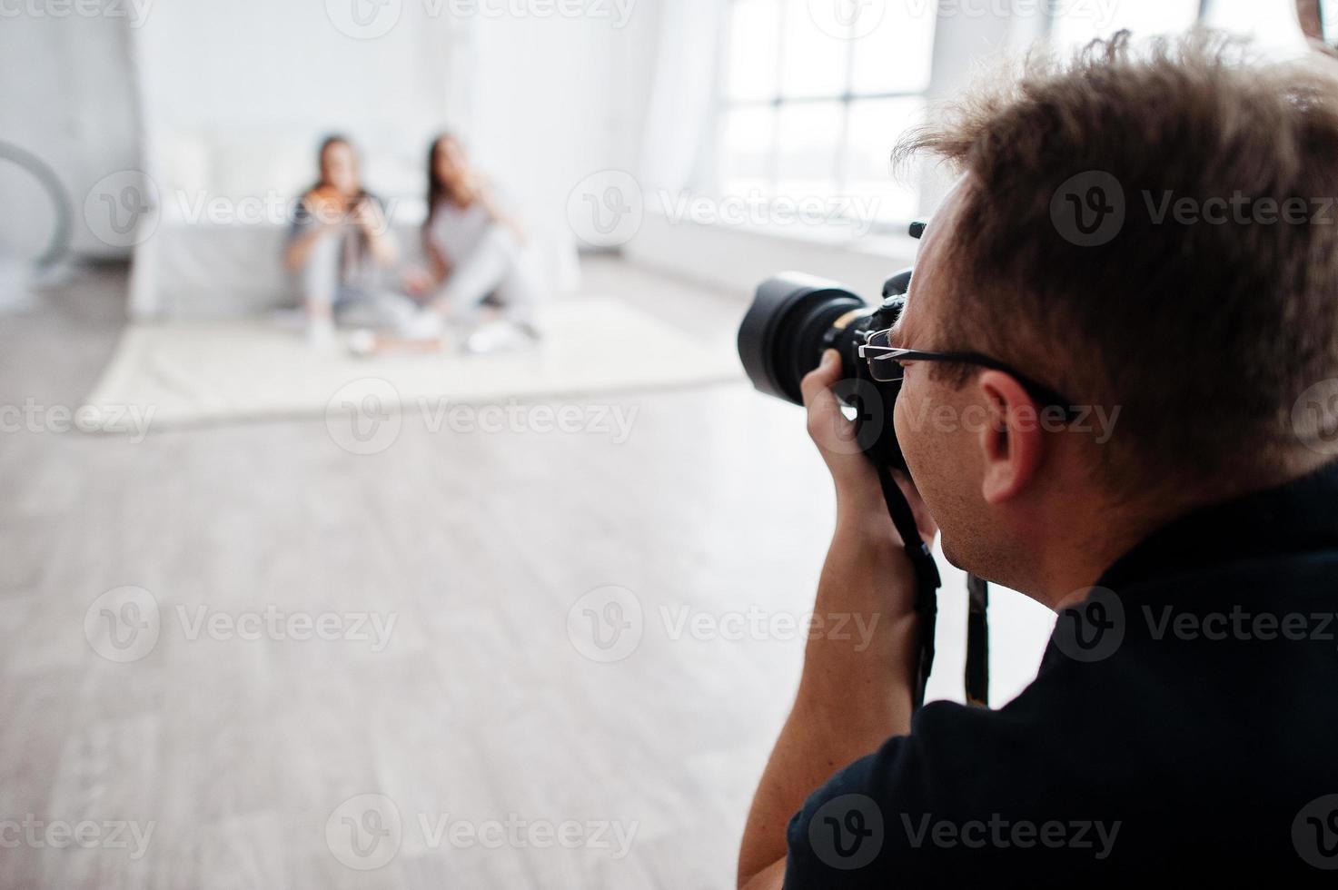man fotograf fotograferar på studio två flickor. professionell fotograf på jobbet. foto