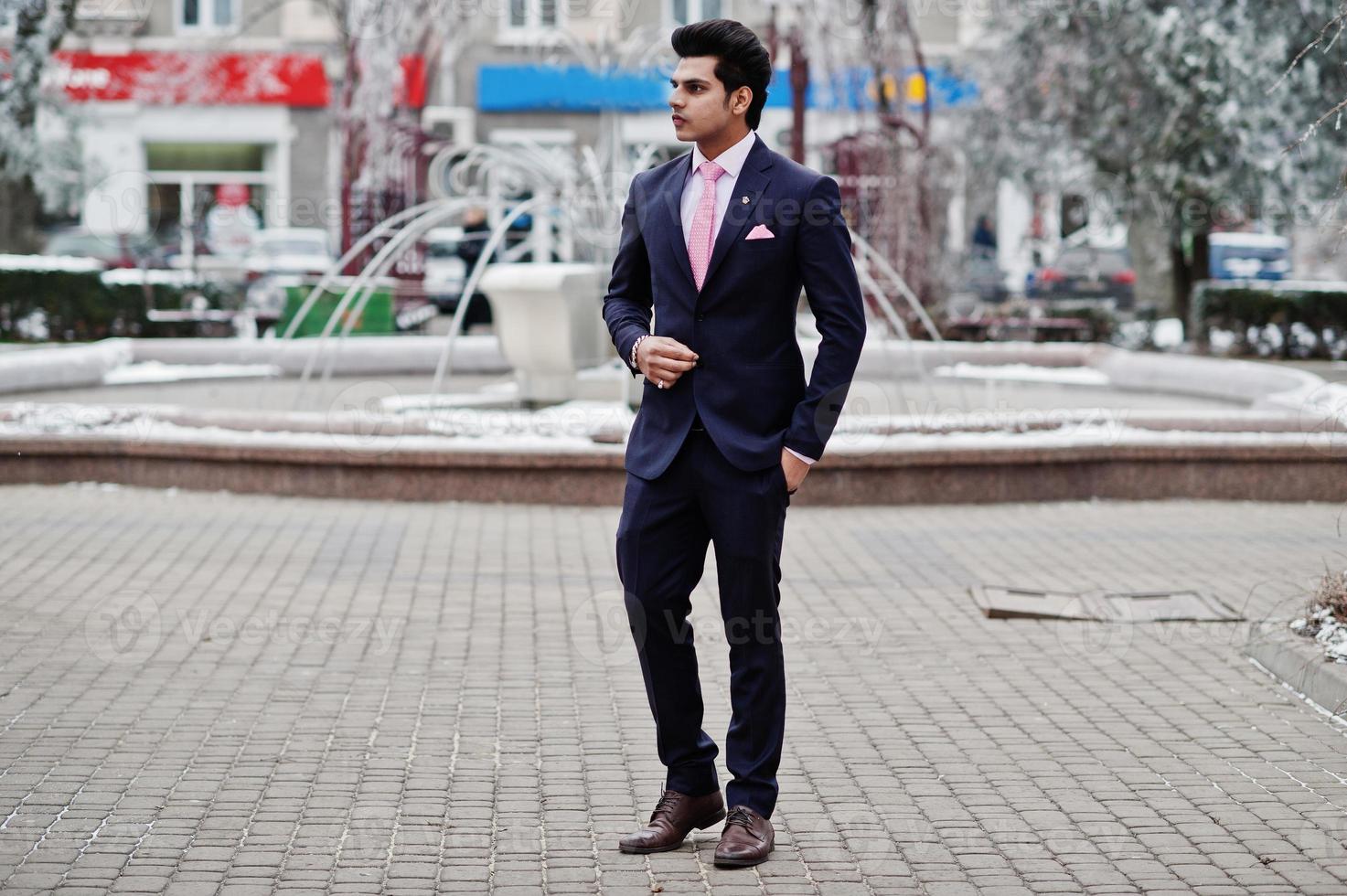 elegant indisk macho man modell på kostym och rosa slips poserade på vinterdagen. foto