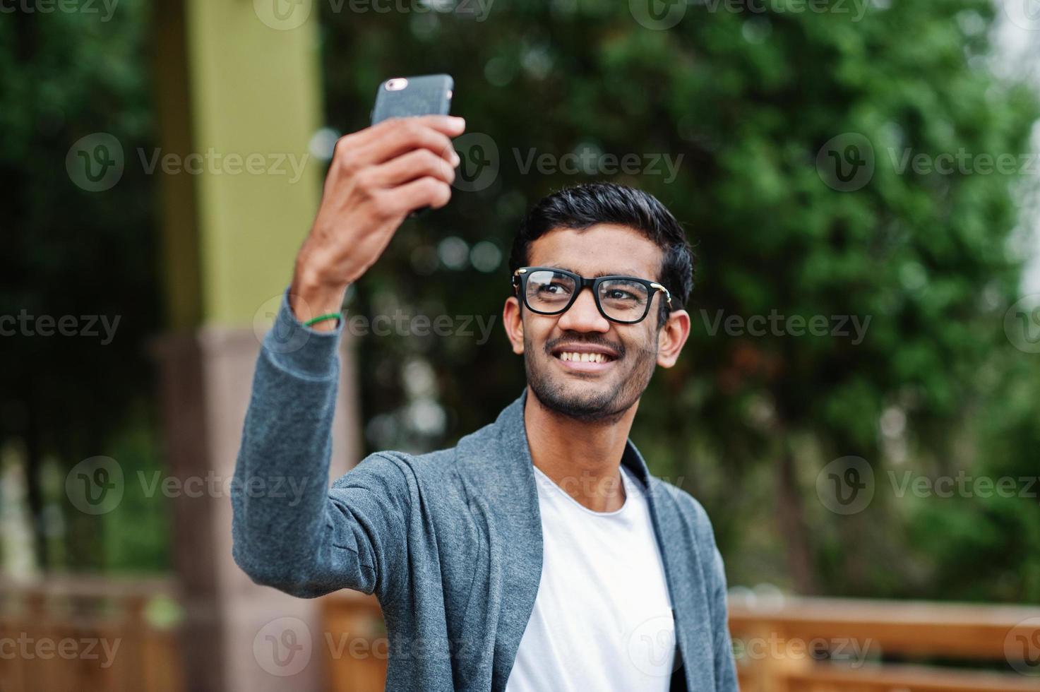 snygg indisk man vid glasögon bär casual poserade utomhus och göra selfie på telefonen. foto