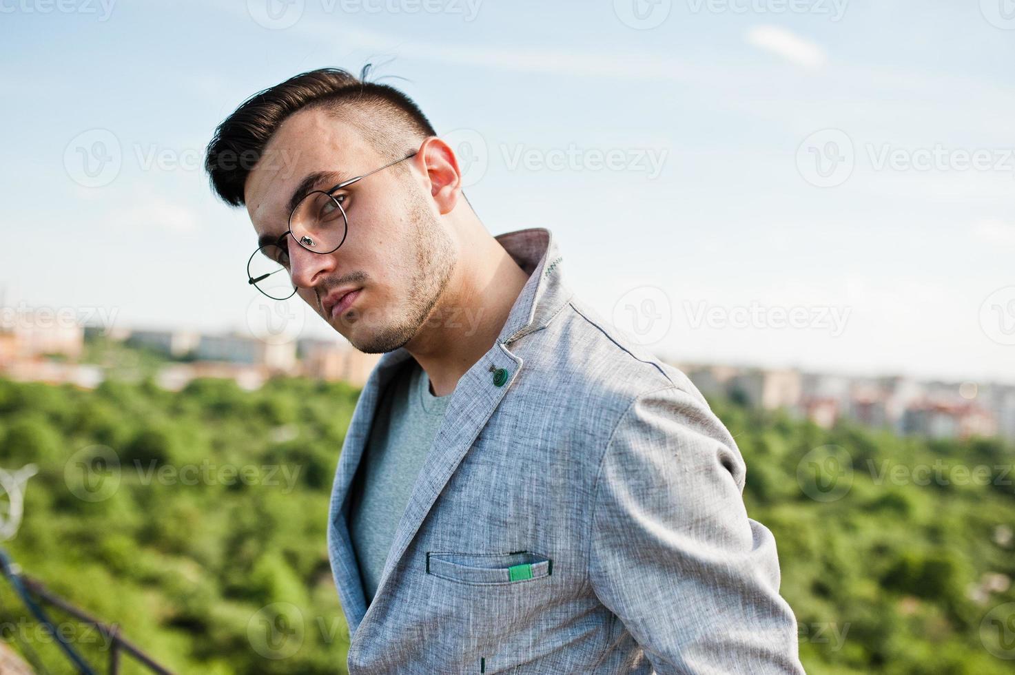 drömmare snygg macho man i grå kostym och glasögon poserade på taket. foto
