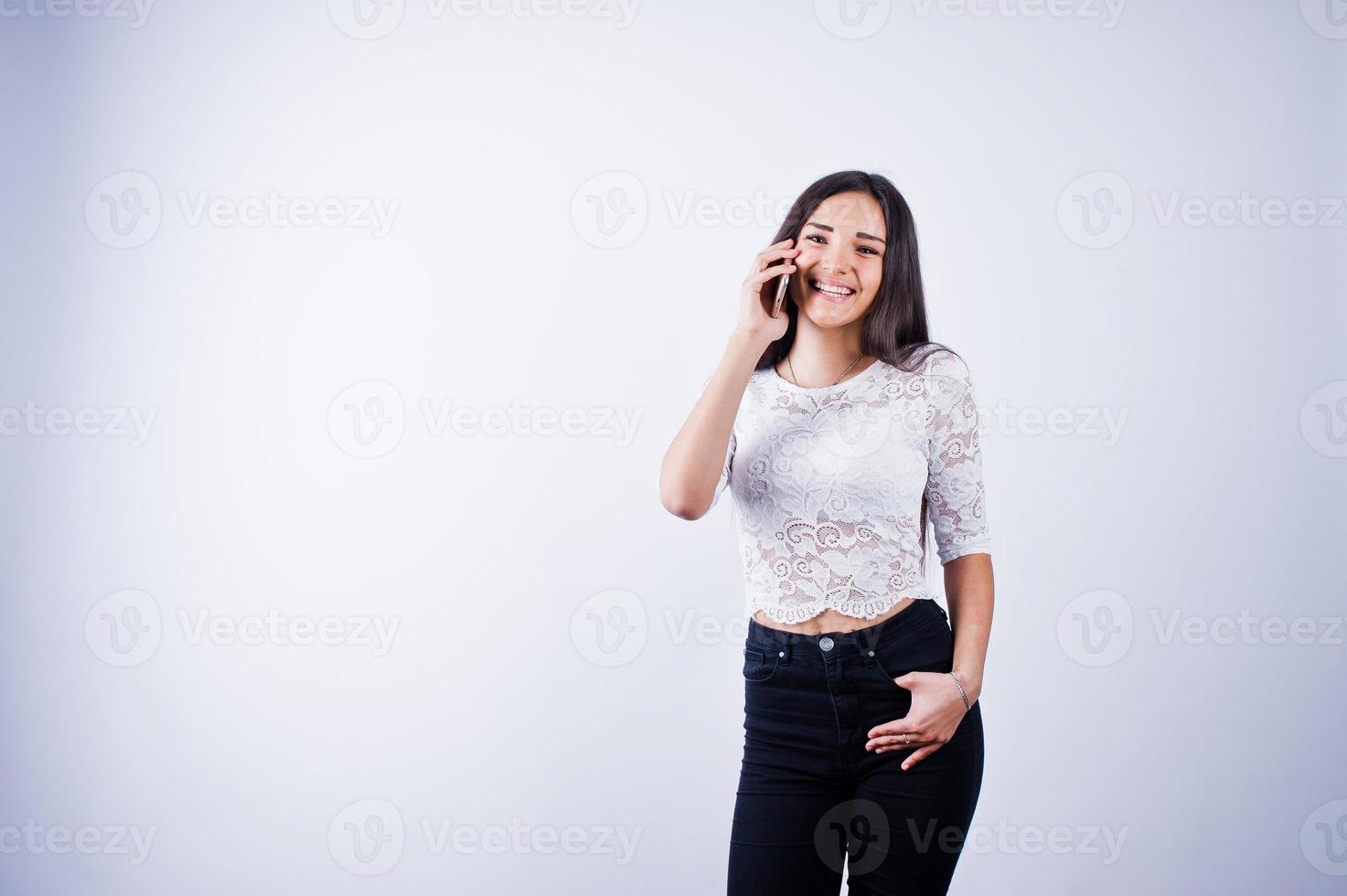 porträtt av en ung vacker kvinna i vit topp och svarta byxor med sin telefon. foto