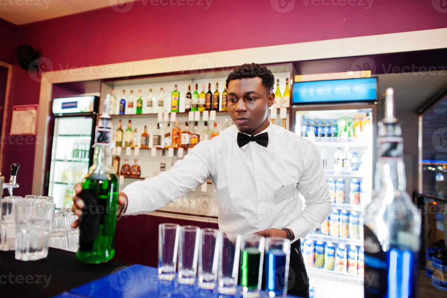 afroamerikansk bartender i baren gör cocktails på skott. beredning av alkoholhaltiga drycker. foto