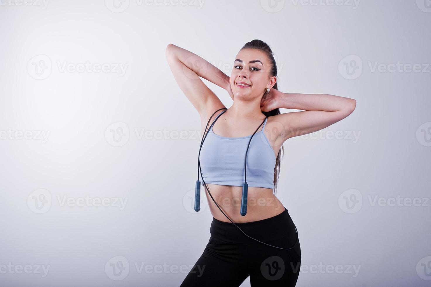 glada attraktiva unga fitness kvinna i topp och svarta leggings med hopprep isolerad över vit bakgrund. foto