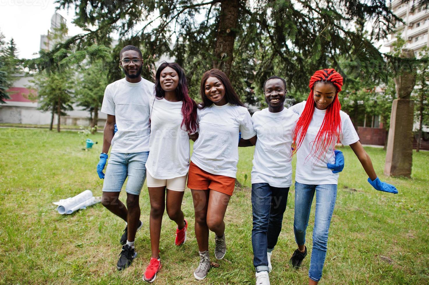 grupp glada afrikanska volontärer kramar tillsammans i parken. Afrika volontärarbete, välgörenhet, människor och ekologi koncept. foto