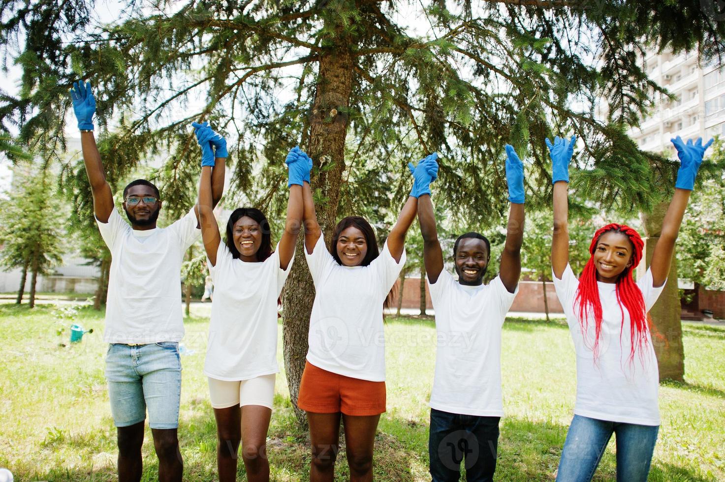 grupp glada afrikanska volontärer håller händerna tillsammans i parken. Afrika volontärarbete, välgörenhet, människor och ekologi koncept. foto