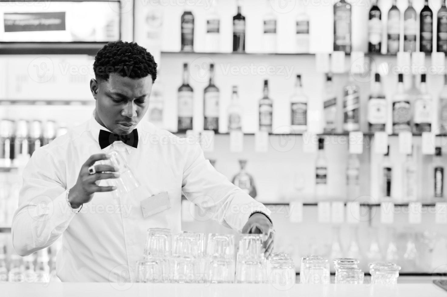 afrikansk amerikansk bartender slitage på fluga rengöringsglasögon i baren. foto