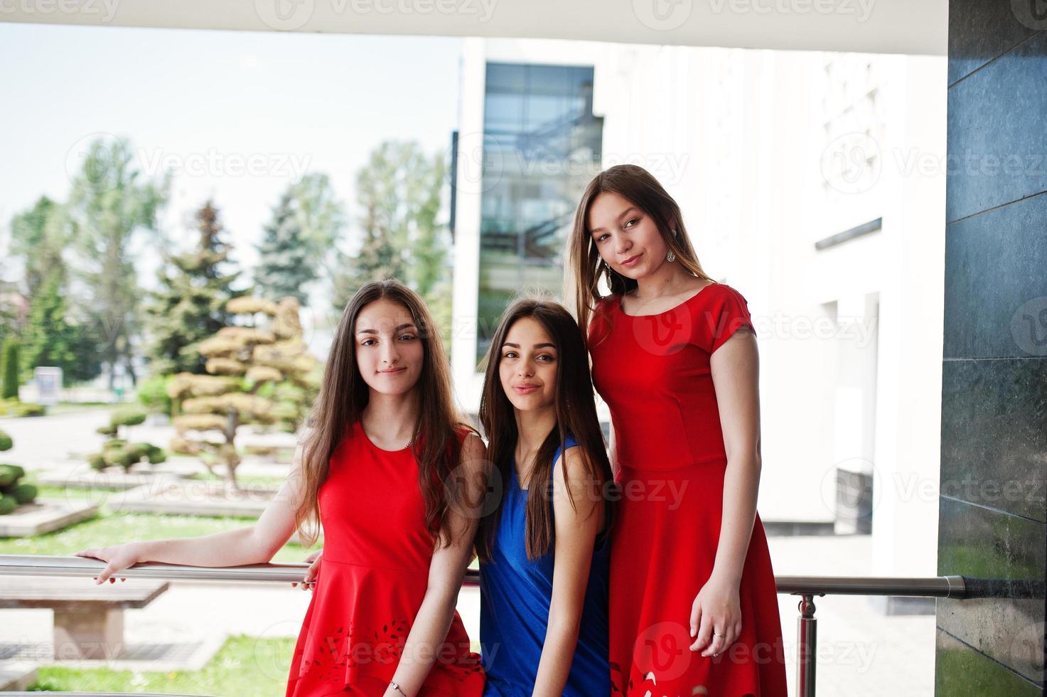 tre tonåringar flicka i blå och röda klänningar poserade utomhus. foto