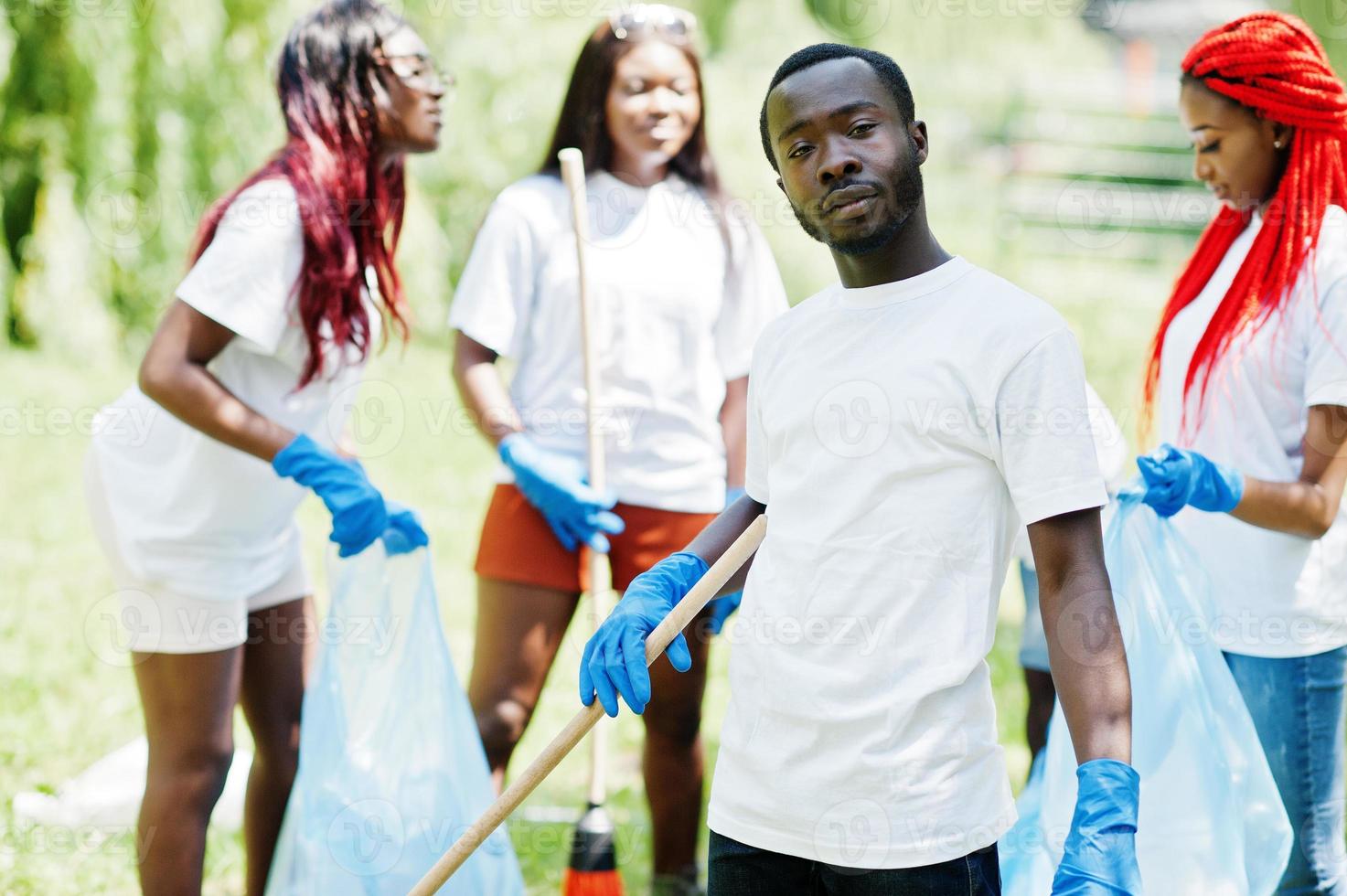 grupp glada afrikanska volontärer med soppåsar rengöringsområde i parken. Afrika volontärarbete, välgörenhet, människor och ekologi koncept. foto