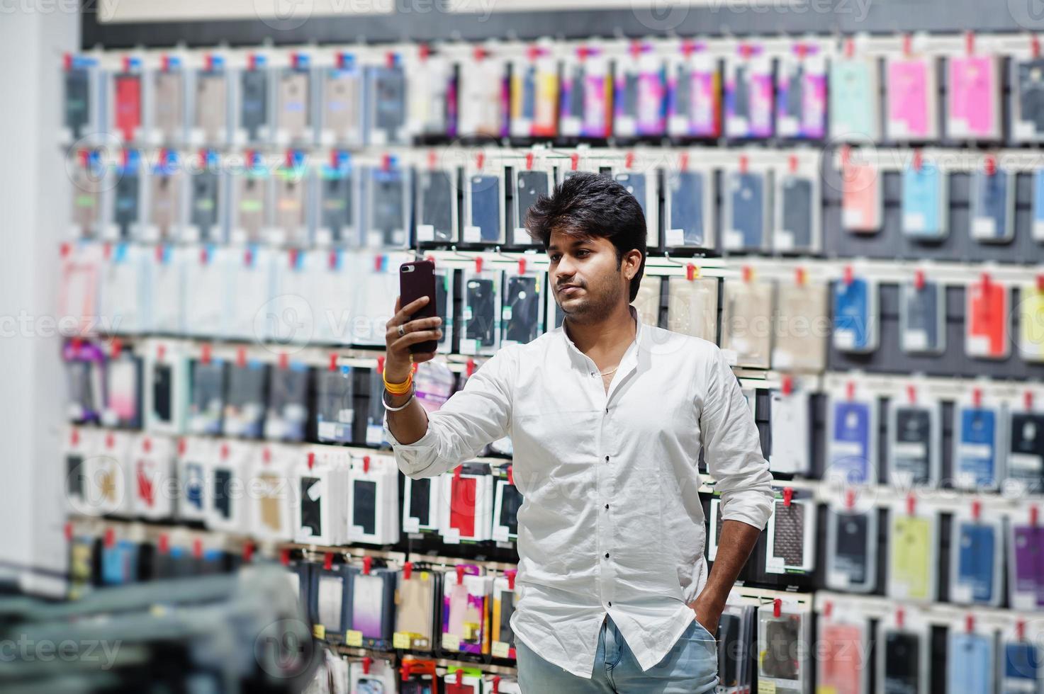 indisk man kund köpare i mobiltelefon butik gör selfie på sin nya smartphone med fodral. sydasiatiska folk och teknik koncept. mobiltelefon butik. foto