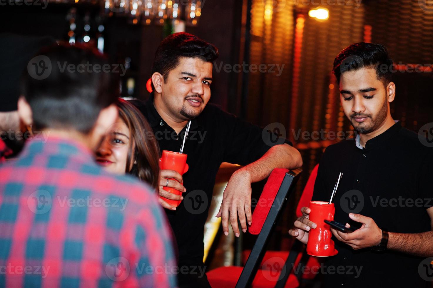 grupp indiska vänner som har kul och vila på nattklubben, dricker cocktails nära bardisken. foto