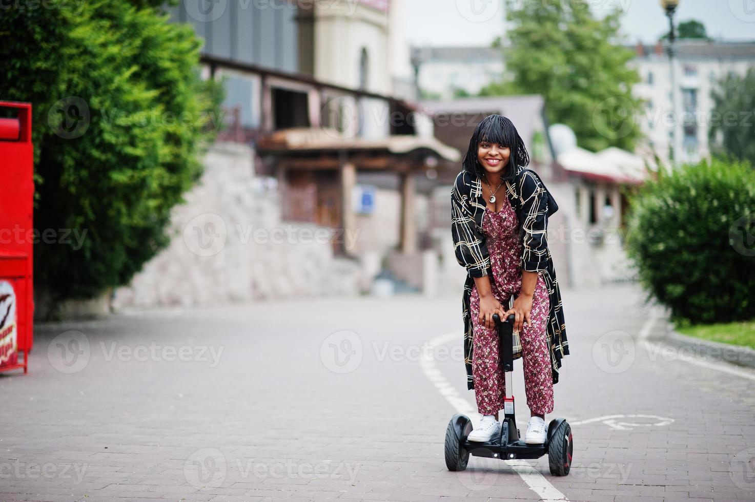 vacker afrikansk amerikansk kvinna som använder segway eller hoverboard. svart flicka på dubbla hjul självbalanserande elektrisk skoter. foto