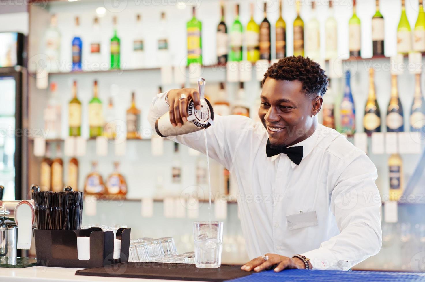 afroamerikansk bartender i baren med shaker. beredning av alkoholhaltiga drycker. foto