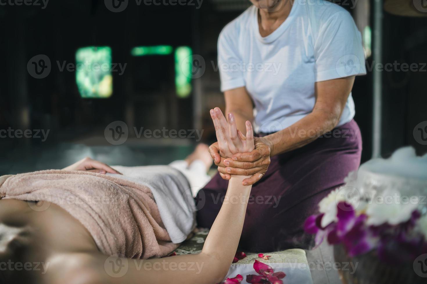massage och spa avslappnande behandling av kontorssyndrom med traditionell thailändsk massagestil med varma stenar. asain kvinnlig massör gör handmassage behandla stress för kvinna. foto
