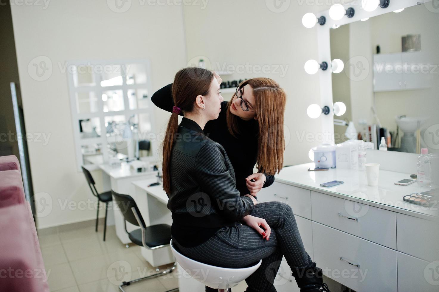 make up artist arbete i hennes skönhet visage studio salong. kvinna som ansöker av professionell make up master. skönhetsklubb koncept. foto