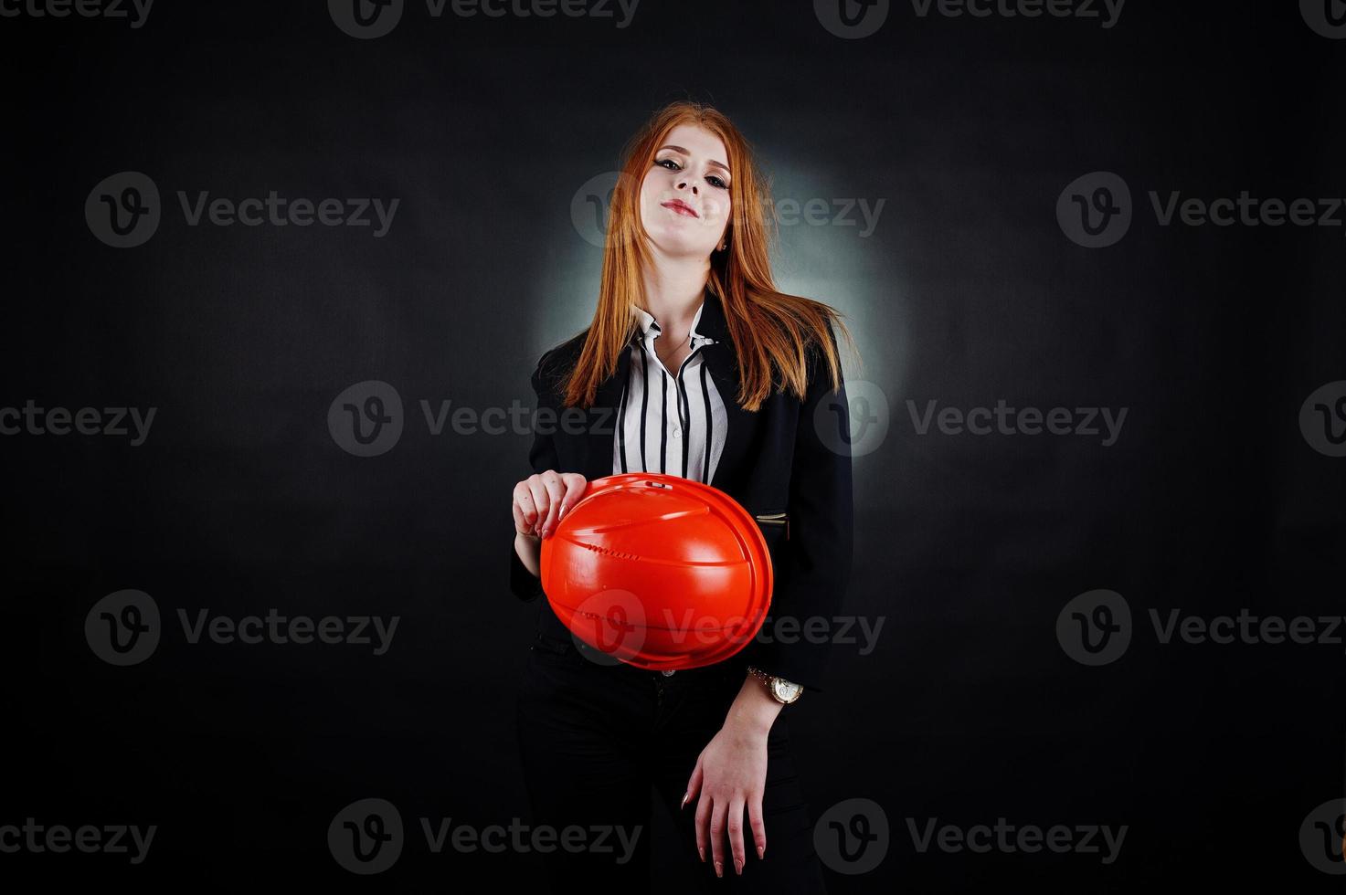 ingenjör kvinna i orange skydda hjälm på studio svart bakgrund. foto