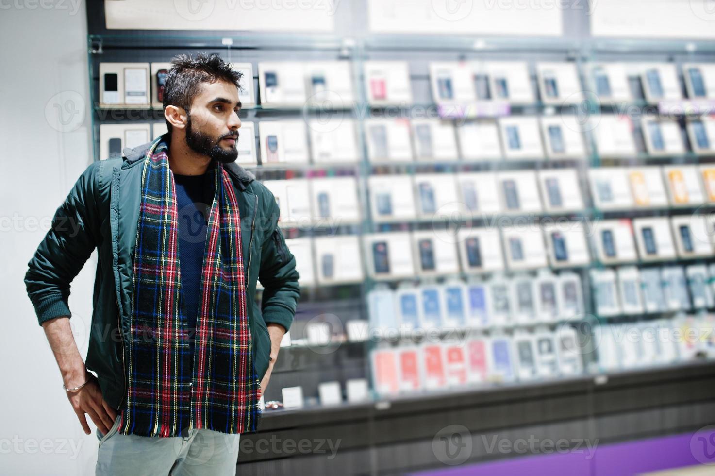 indisk skägg man kund köpare i jacka på mobiltelefon butik. sydasiatiska folk och teknik koncept. mobiltelefon butik. foto