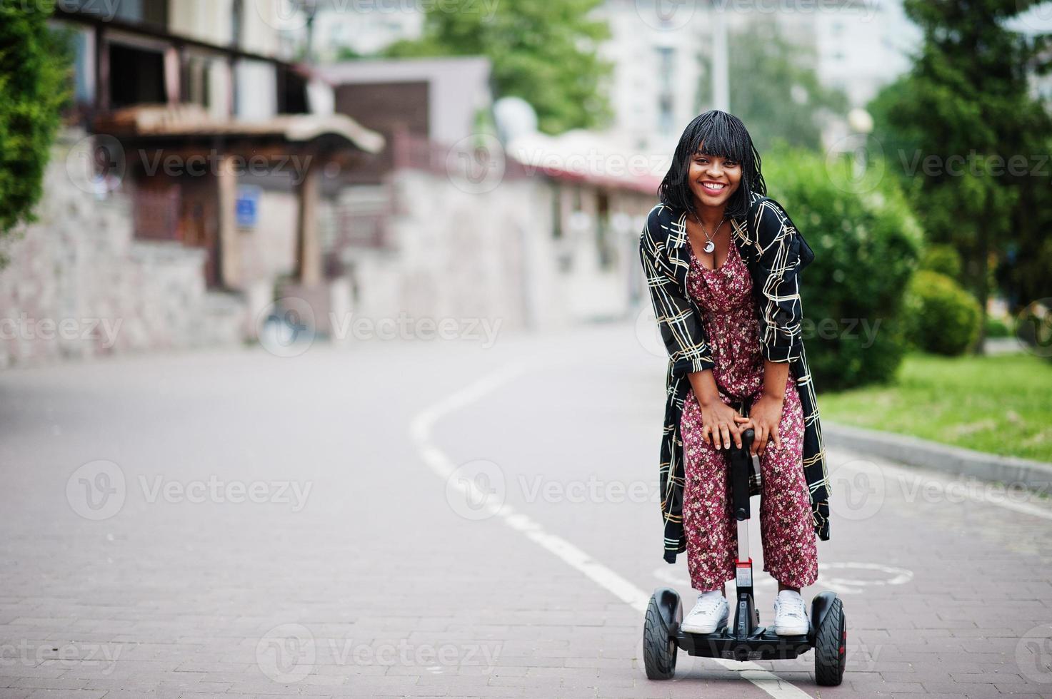 vacker afrikansk amerikansk kvinna som använder segway eller hoverboard. svart flicka på dubbla hjul självbalanserande elektrisk skoter. foto