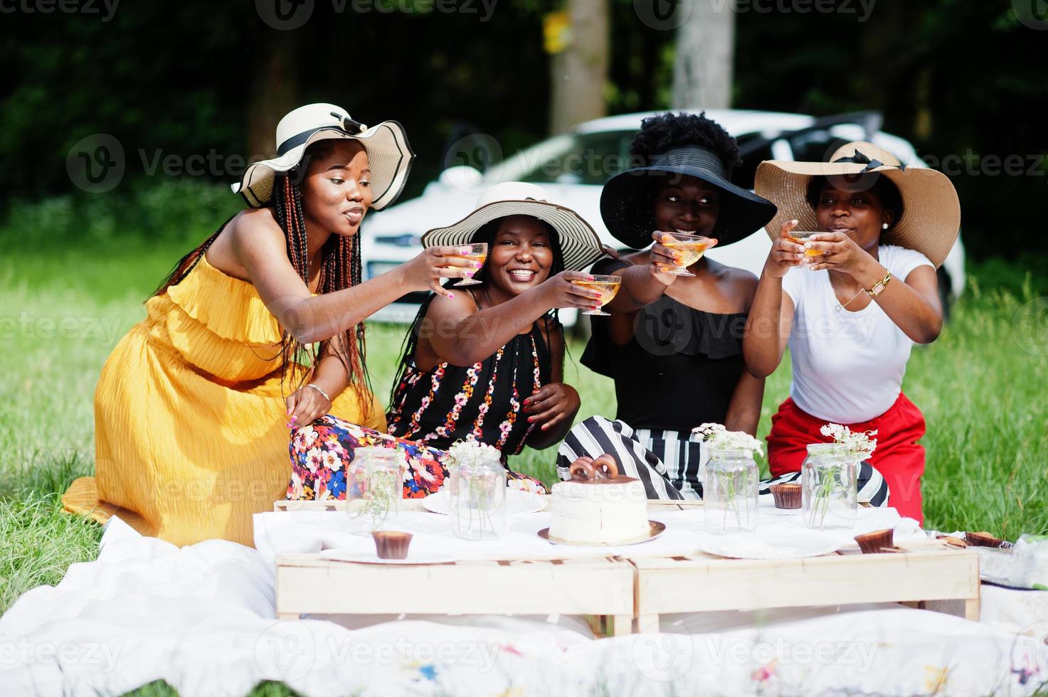 grupp afroamerikanska flickor som firar födelsedagsfest och klirrande glasögon utomhus med inredning. foto