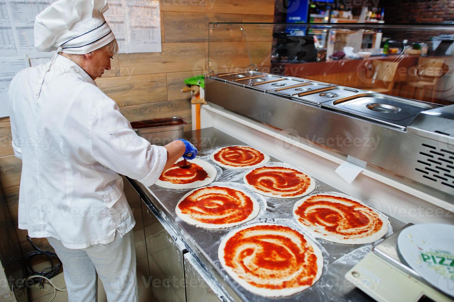 kvinnlig kock förbereder pizza i restaurangkök. foto