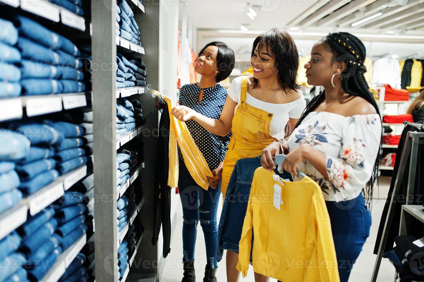 tre afrikansk kvinna att välja kläder i butik. shopping dag. de köper jeans. foto