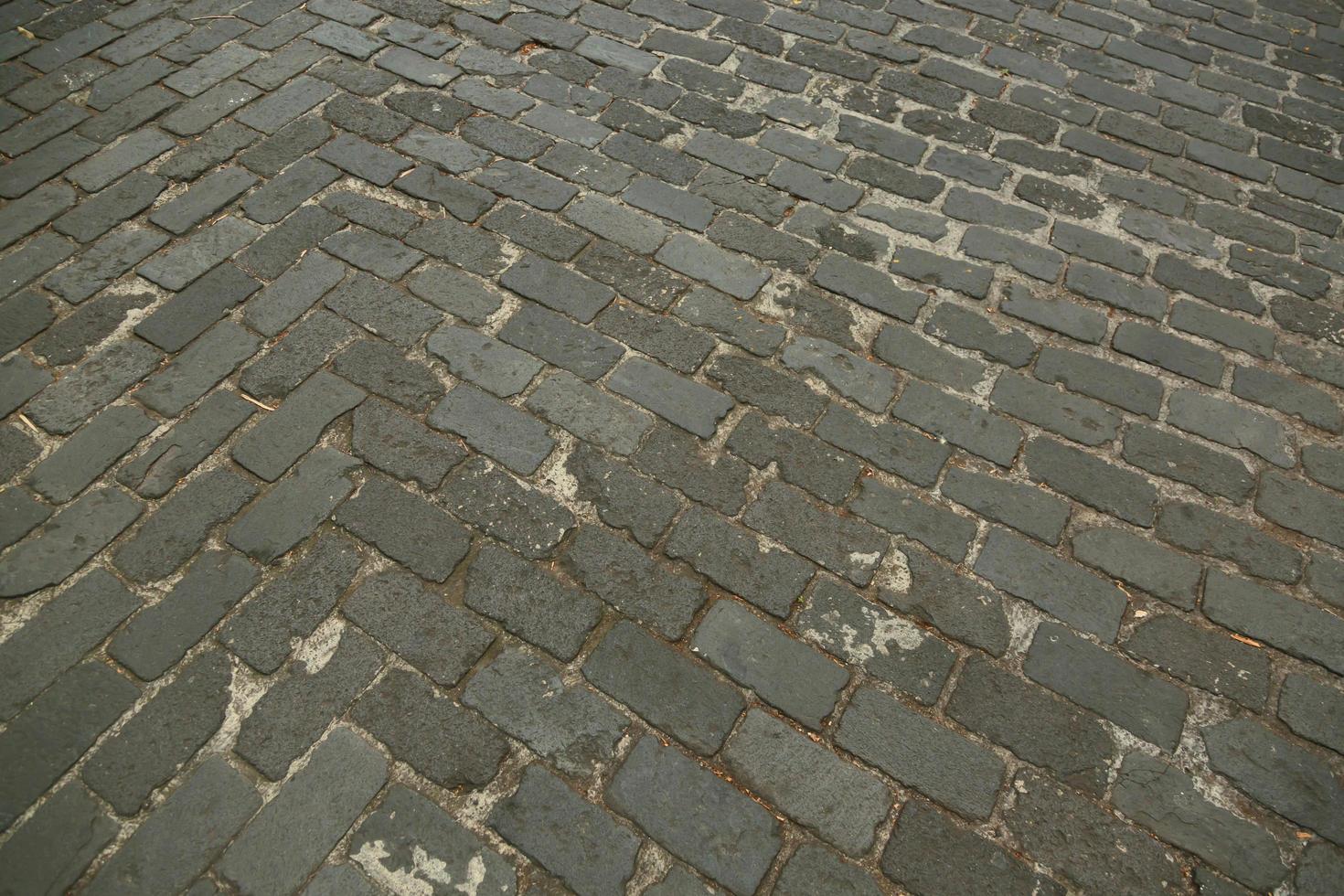 gammal gata väg asfalterad yta sten trottoar gångväg texturmönster. granit kullersten trottoaren bakgrund. abstrakt bakgrund av gamla kullersten trottoaren vintage stil Europa. foto