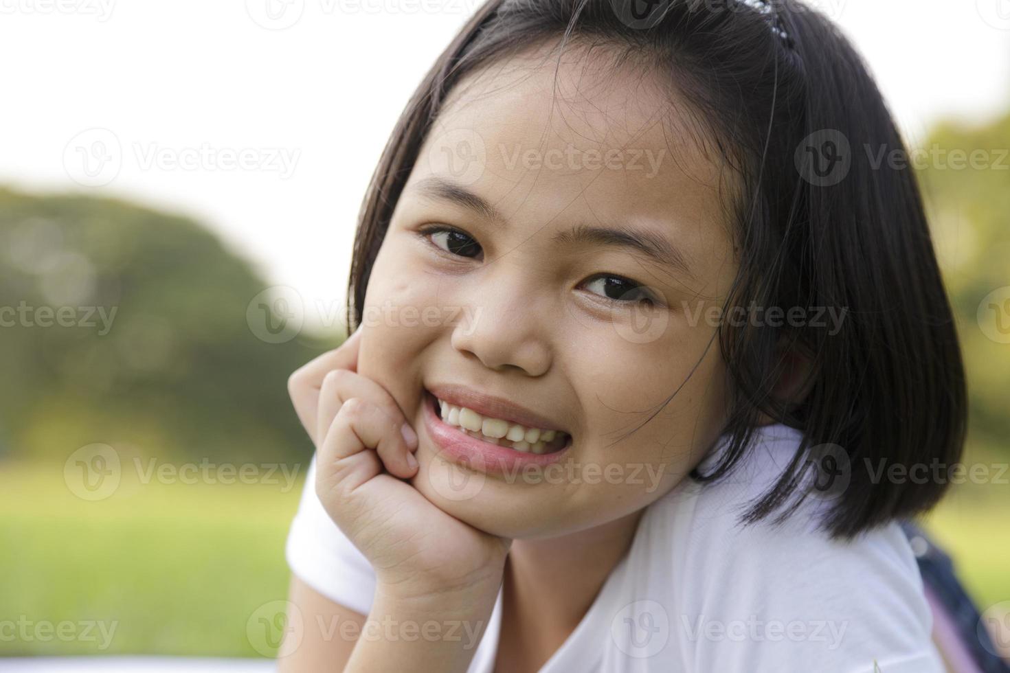 asiatisk liten flicka koppla av och ler glatt i parken foto