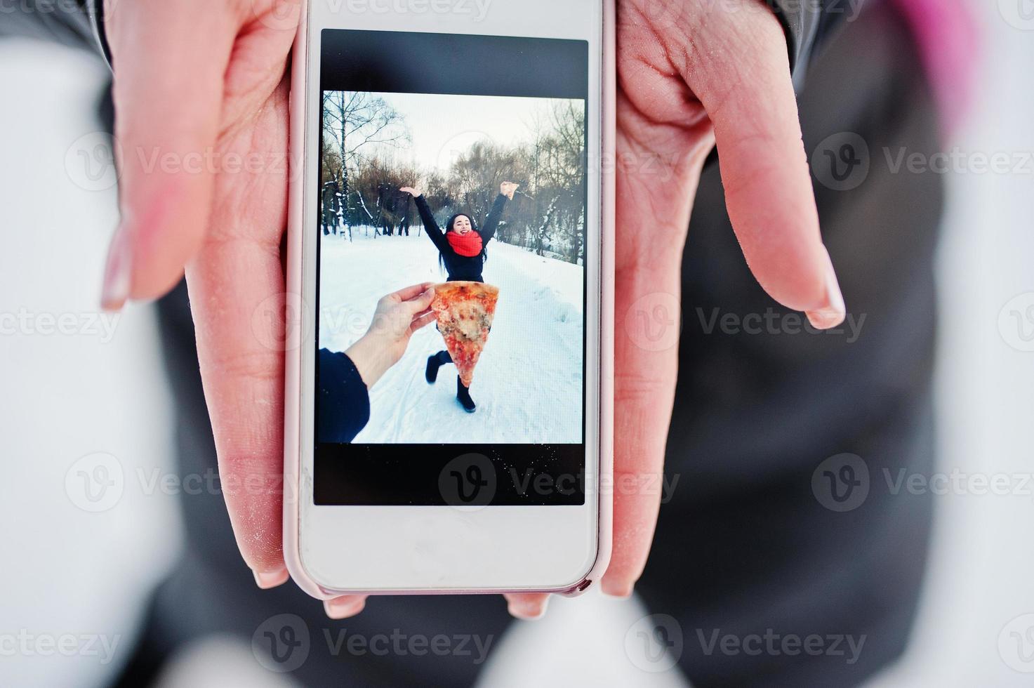 flicka i skärmen på telefonen med pizza. roligt koncept. foto