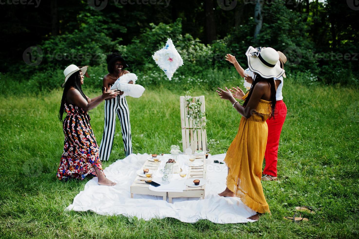 grupp afroamerikanska tjejer som firar födelsedagsfest och har kul med kuddar utomhus med inredning. foto