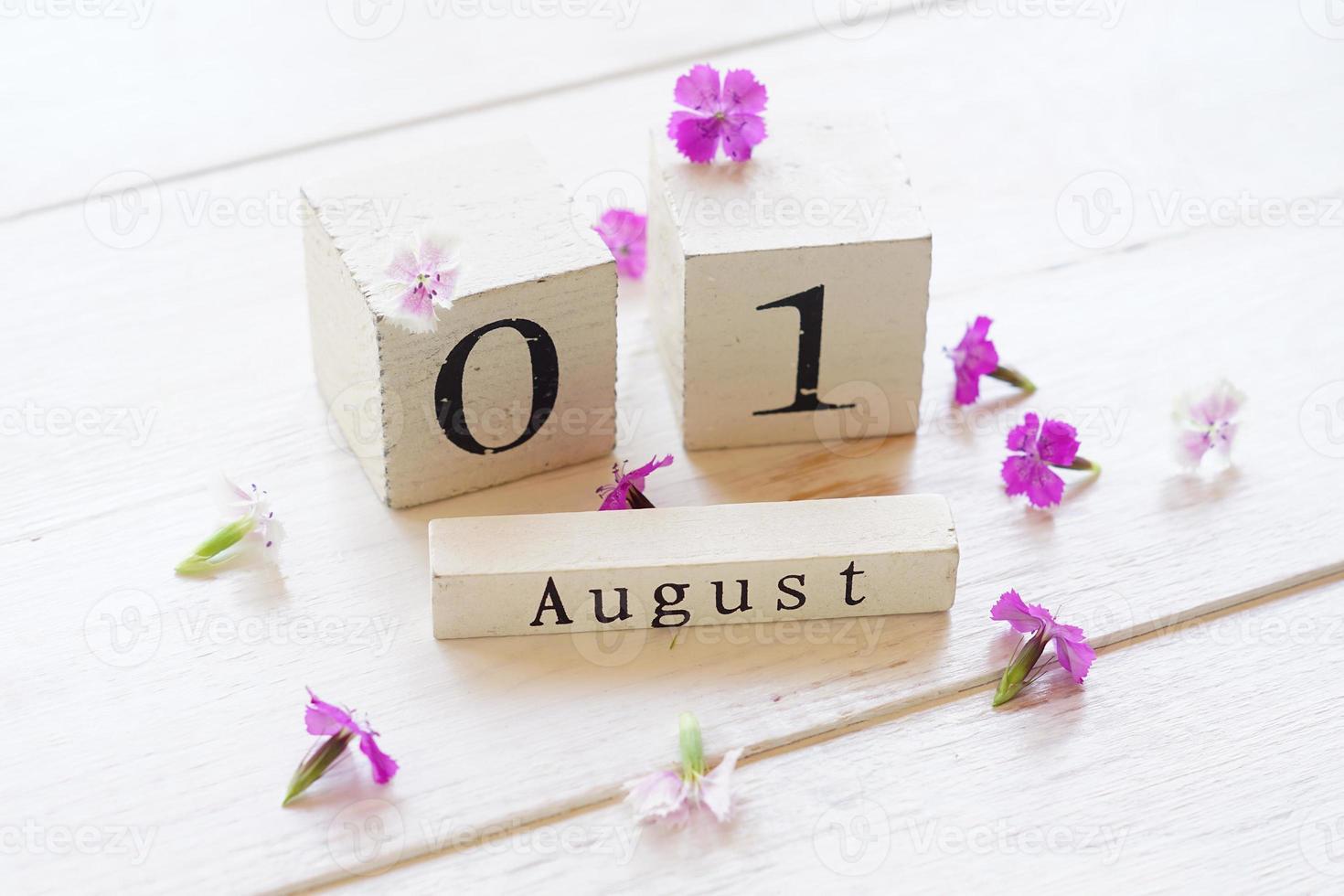 1 augusti, färgglad bakgrund med kub-träkalender och rosa blommor foto