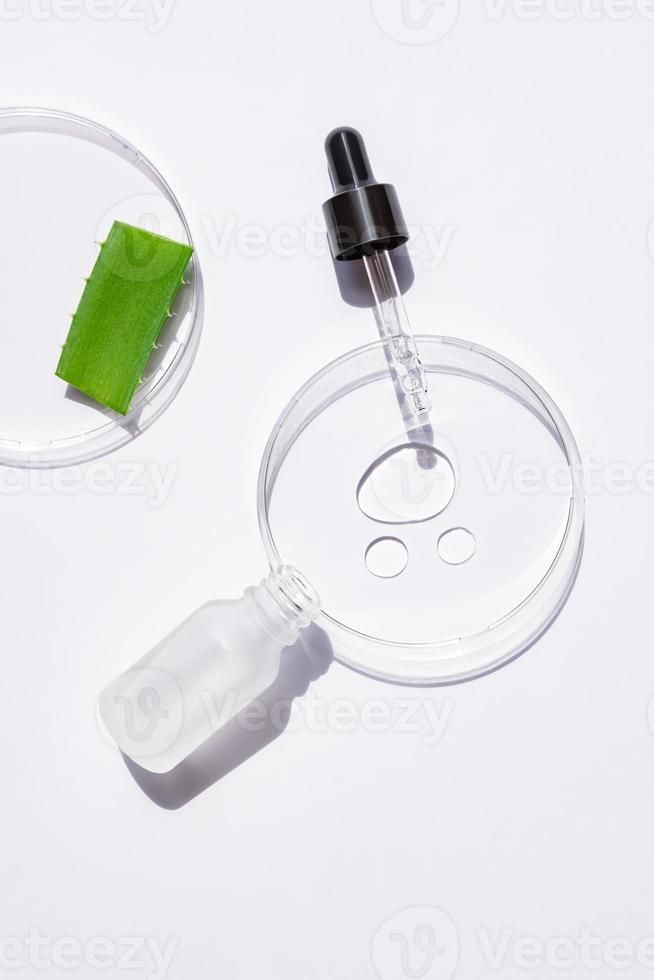 petriskål i glas med droppe av aloe gel för ansikte och droppare av retinol eller fuktgivande serum, eterisk olja med örtextrakt. kosmetiska produkter. dermatologi vetenskap kosmetiskt laboratorium foto