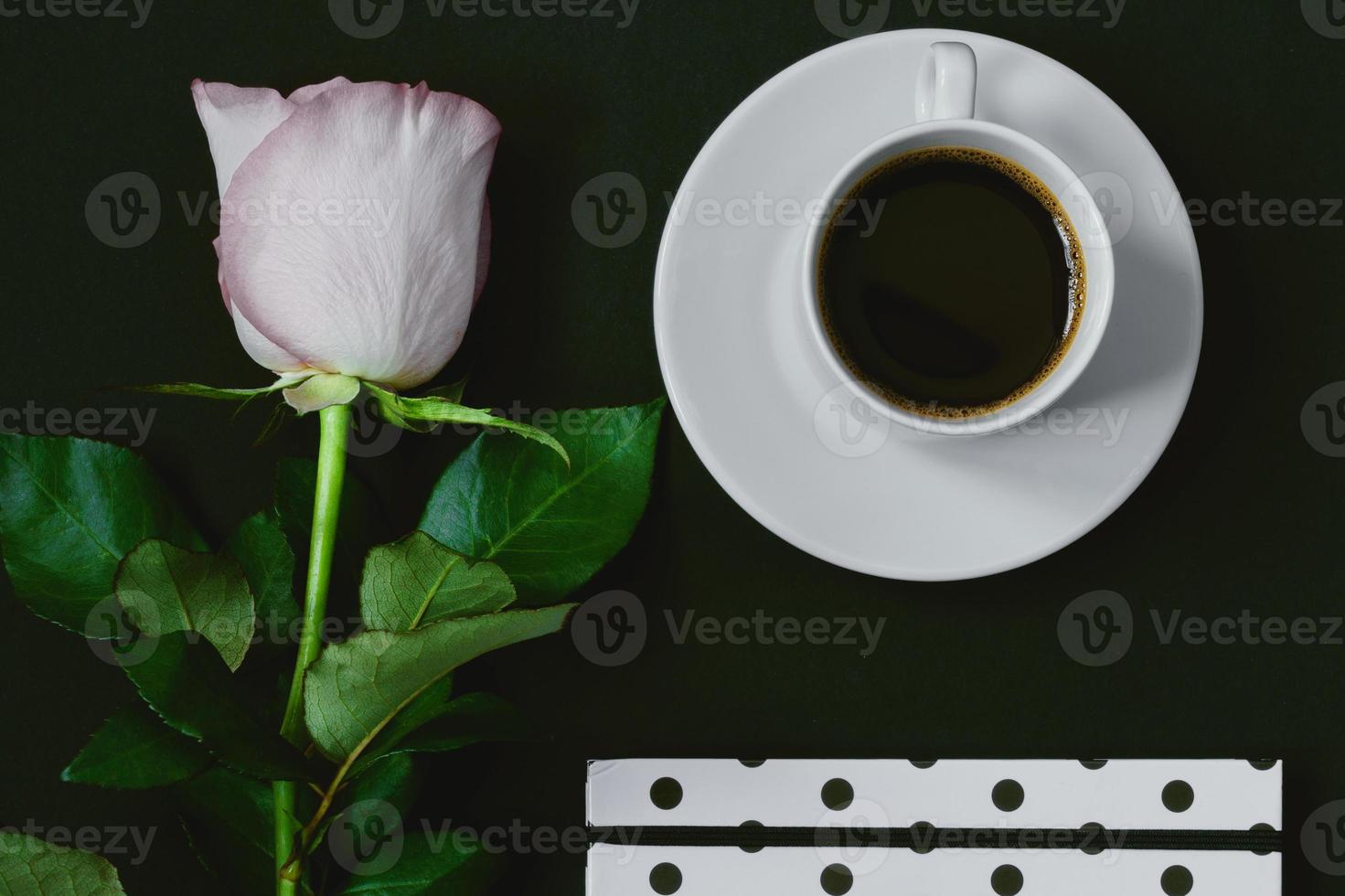 kopp svart kaffe, anteckningsbok och rosa ros på svart bakgrund, ovanifrån, kopieringsutrymme. tonad foto